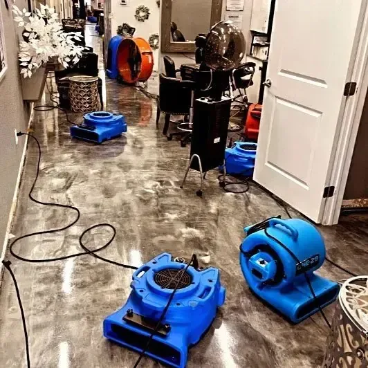 Air movers drying a wet floor beside a hallway