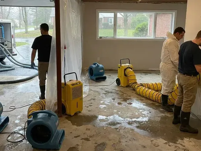 Workers with air movers and ducts on a wet floor