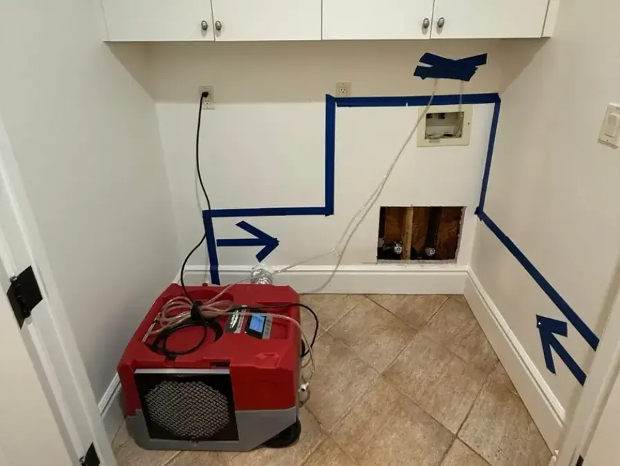 Blue tape outlining a laundry wall above a red dehumidifier