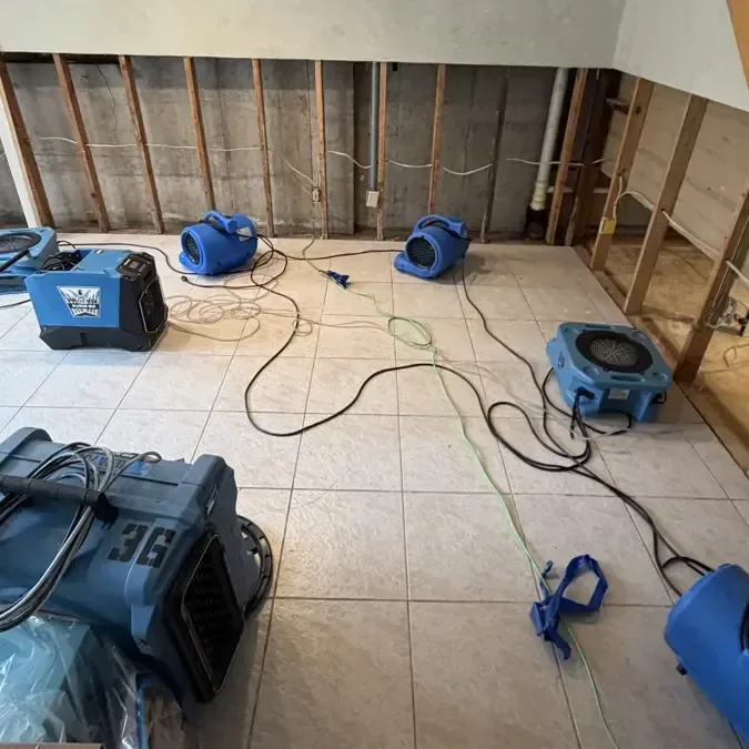 Drying equipment on tile beside exposed wood wall studs