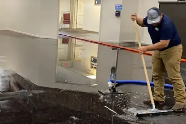 Technician moving water toward an extraction hose in an office