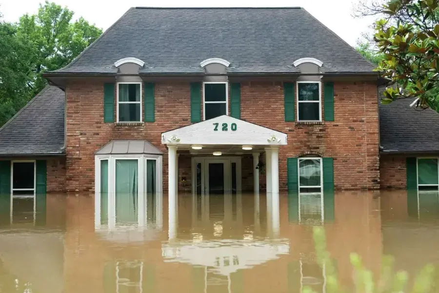 Brown floodwater surrounding a brick house